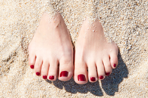 Manikürte Füße im Sand